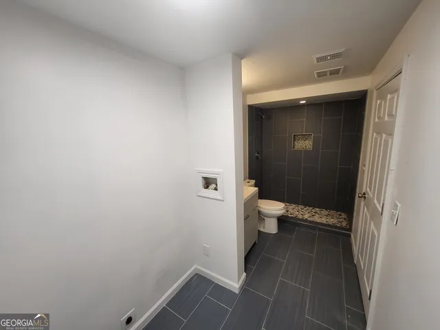 a bathroom with a granite countertop toilet and a sink