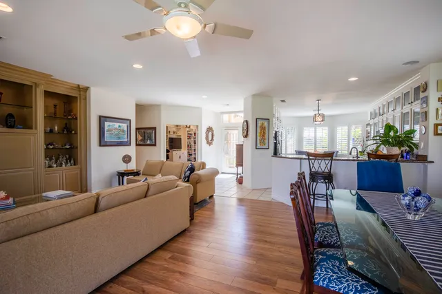 a living room with furniture kitchen area and a chandelier