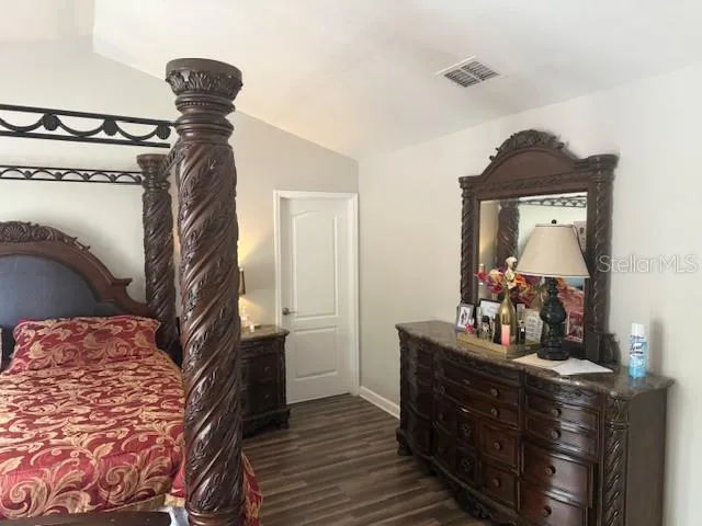 a bedroom with a bed and a mirror on the dresser