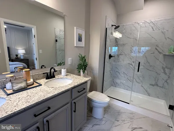a bathroom with a granite countertop sink a toilet a mirror and shower