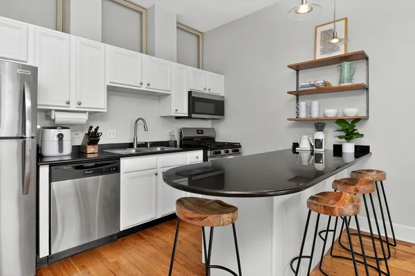 a kitchen with granite countertop a sink dishwasher stove and oven with wooden floor