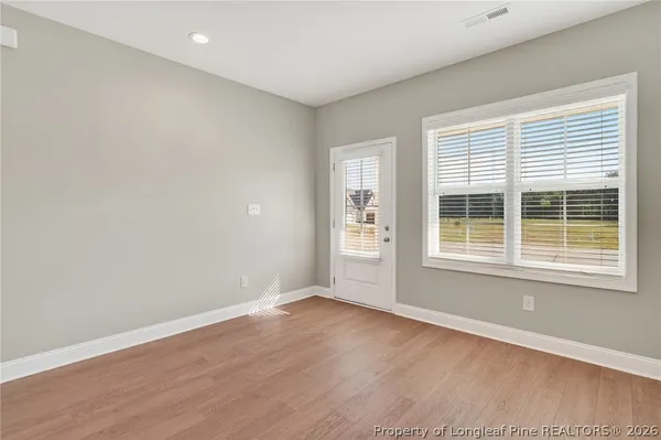 an empty room with wooden floor and windows