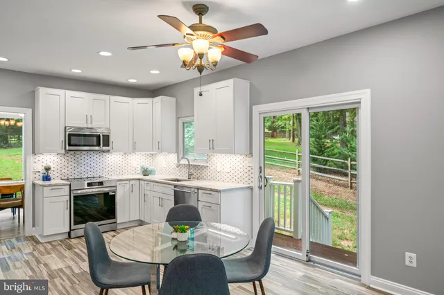 a kitchen with kitchen island granite countertop a dining table chairs and white cabinets