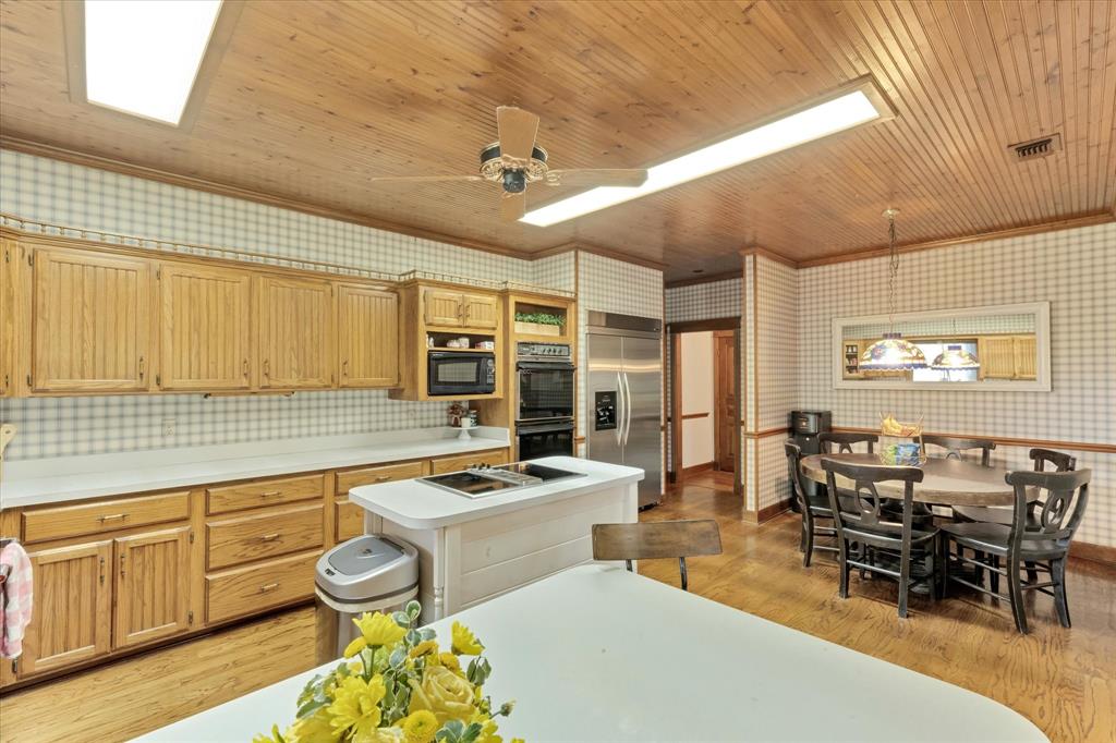 2717 Clear Lake Road Weatherford, TX 76087 - Photo 12 of 40 Spacious kitchen featuring light wood cabinetry, a central island with cooktop, stainless steel appliances, sub-zero refrigerator and wood-finish flooring