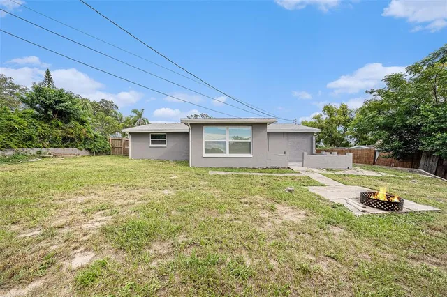 a backyard of a house with table and chairs and wooden fence