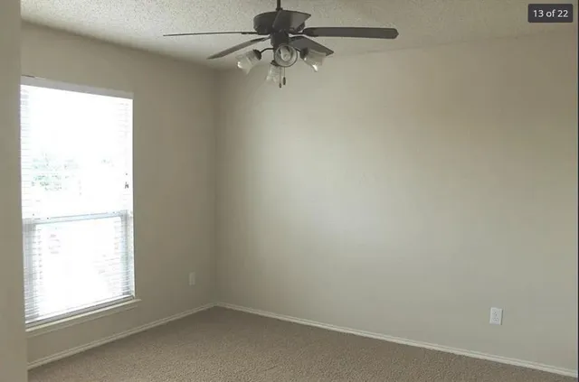 an empty room with a window and a fan
