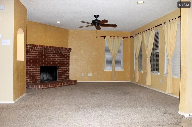 a view of an empty room with a fireplace and a window
