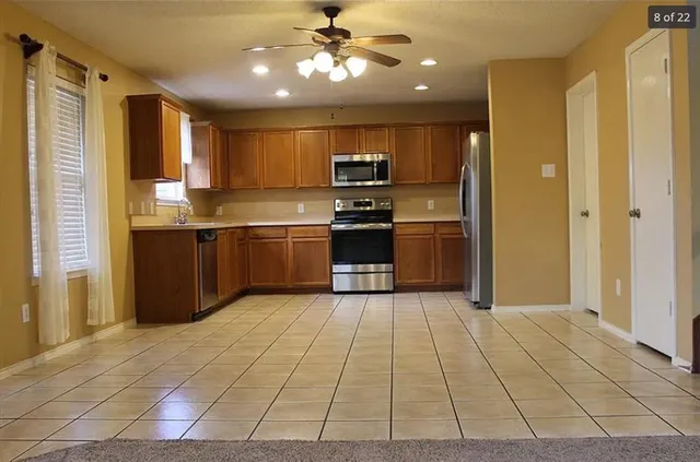 a large kitchen with stainless steel appliances granite countertop a refrigerator and a sink