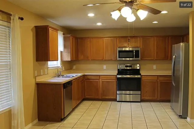 a kitchen with a sink stainless steel appliances a counter top space cabinets and a window