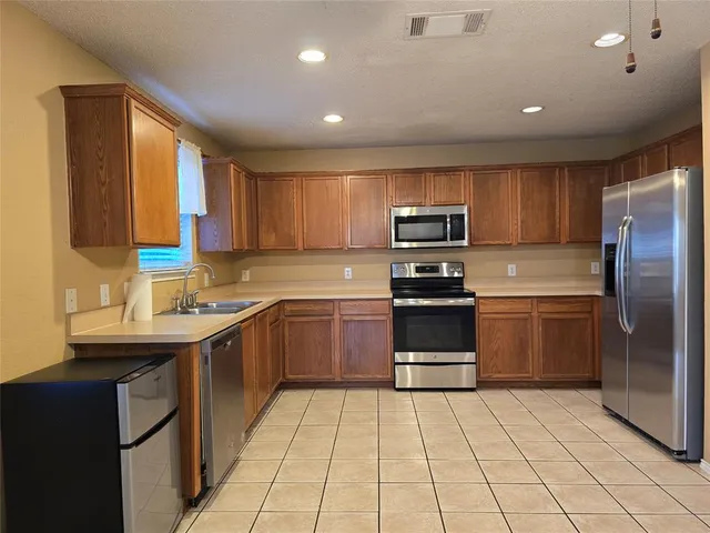 a kitchen with kitchen island granite countertop a stove top oven cabinets a sink and a refrigerator