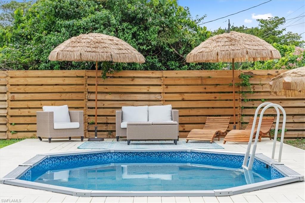 3999 Guava Drive Naples, FL 34104 - Photo 19 of 24 a view of a pool with a table and chairs under an umbrella