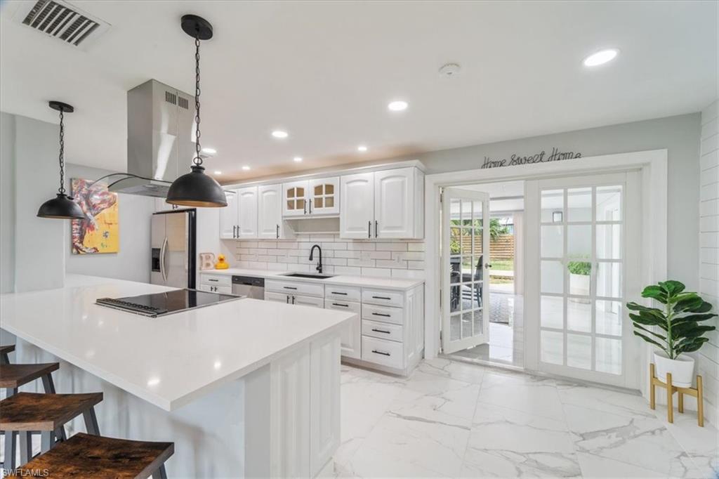 3999 Guava Drive Naples, FL 34104 - Photo 6 of 24 a kitchen with stainless steel appliances kitchen island granite countertop a stove a sink and a refrigerator
