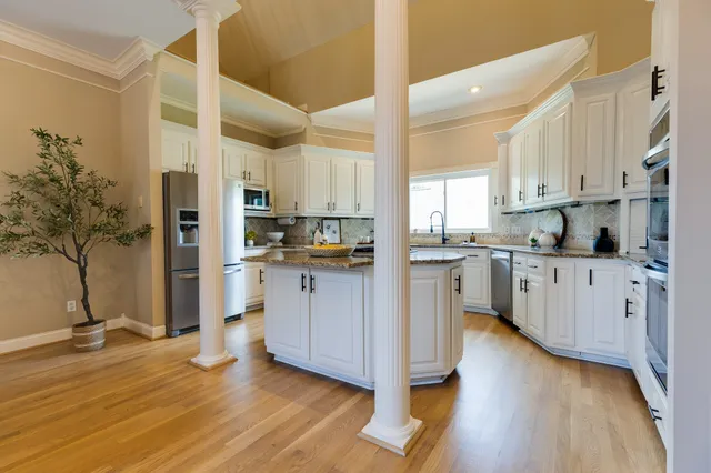 a kitchen with stainless steel appliances granite countertop a stove a sink dishwasher and cabinets with wooden floor