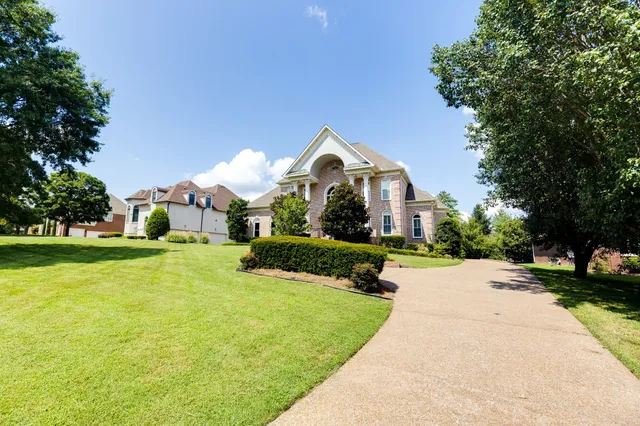 a view of a house with a yard and large trees