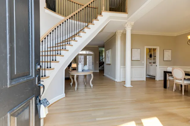 a dining room with wooden floor a chandelier a glass table and chairs