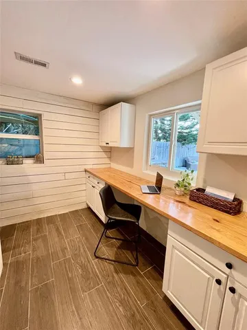 a room with a table chairs wooden floor and a window