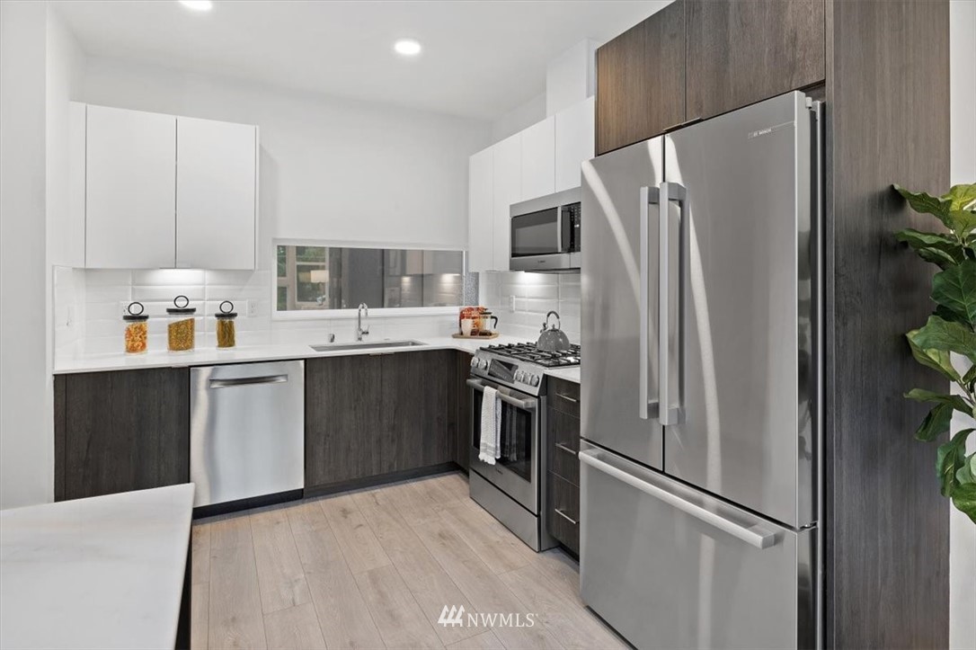 1271 North 145th Street Seattle, WA 98133 - Photo 11 of 32 a kitchen with stainless steel appliances a refrigerator sink and cabinets