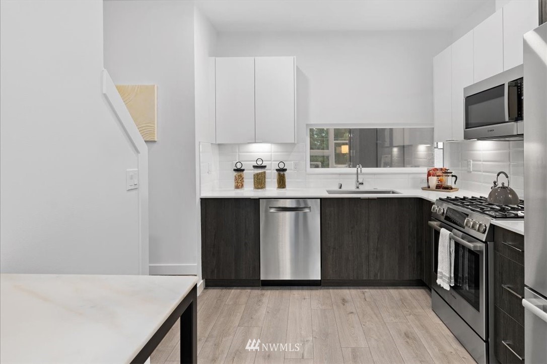 1271 North 145th Street Seattle, WA 98133 - Photo 12 of 32 a kitchen with stainless steel appliances a sink stove and cabinets