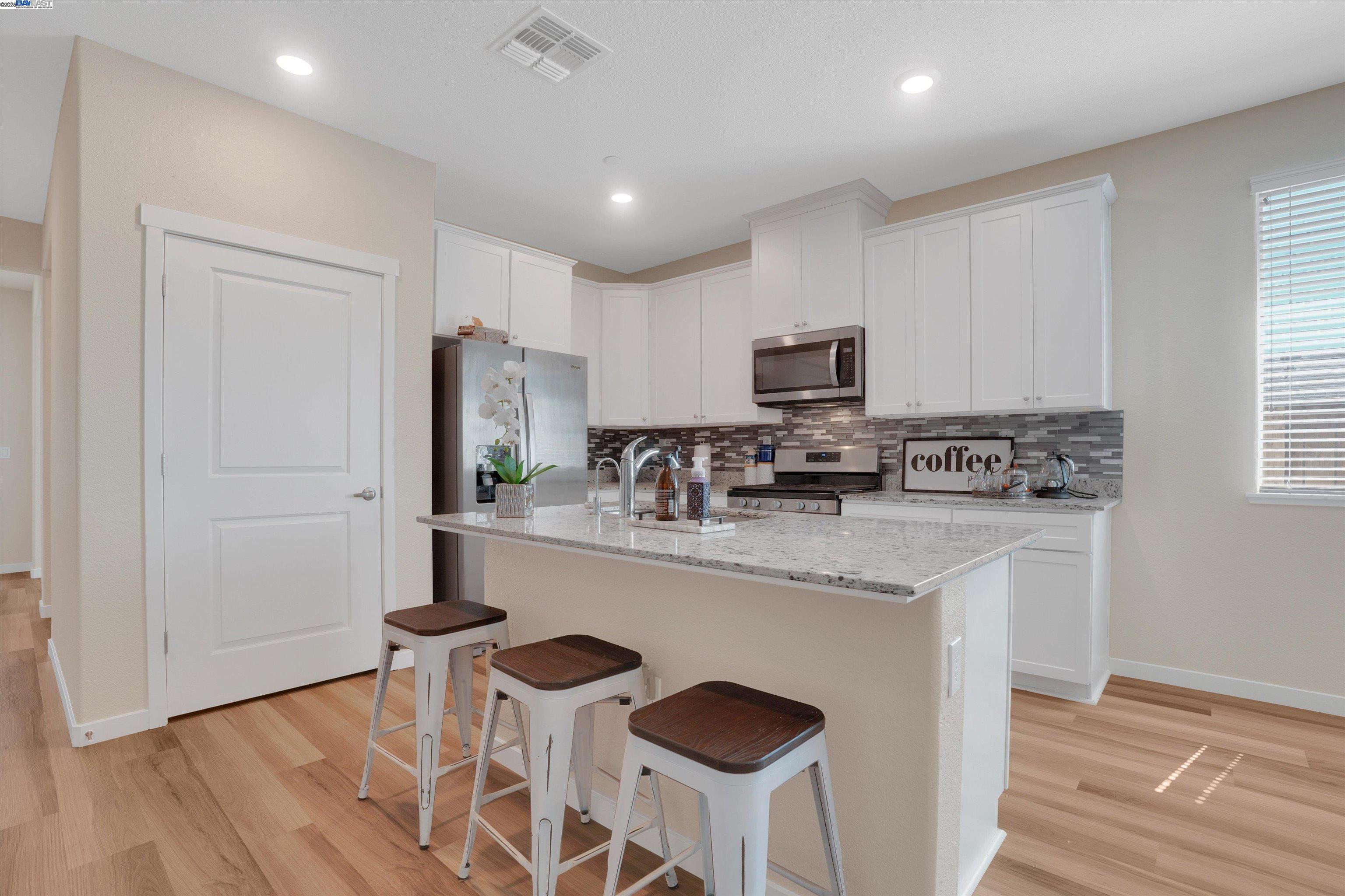 2211 Lavender Place Rio Vista, CA 94571 - Photo 12 of 36 a kitchen with stainless steel appliances granite countertop a stove a sink a refrigerator white cabinets and wooden floor
