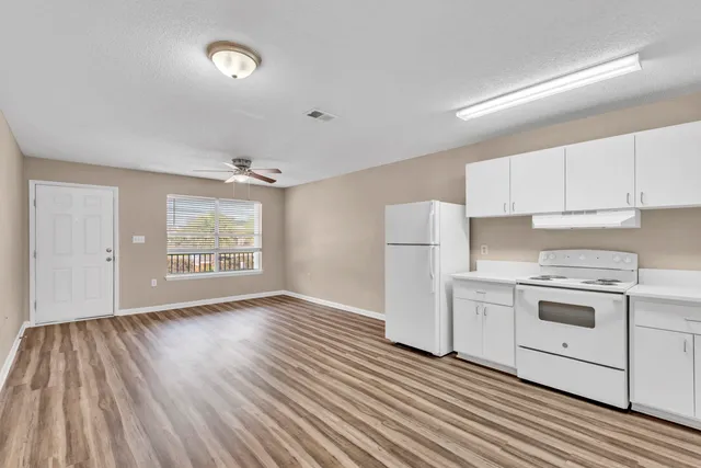 a kitchen with a hard wood floor and white appliances