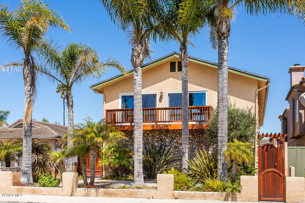 a front view of multiple houses with palm trees