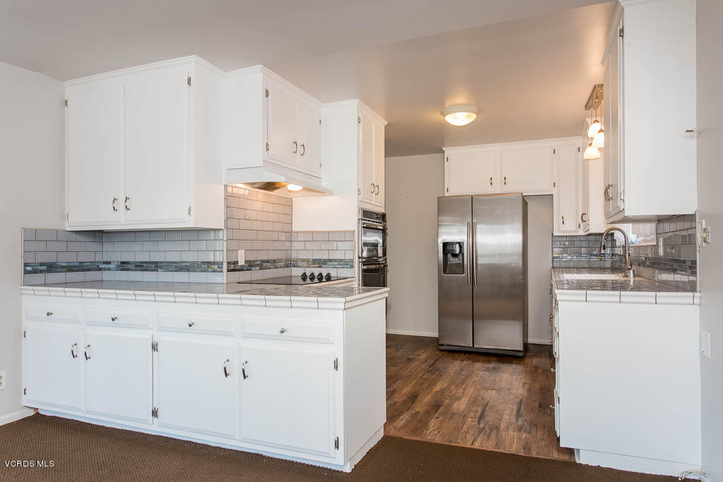 5051 Island View Street Oxnard, CA 93035 - Photo 13 of 38 a kitchen with stainless steel appliances granite countertop a refrigerator a oven and white cabinets with wooden floors