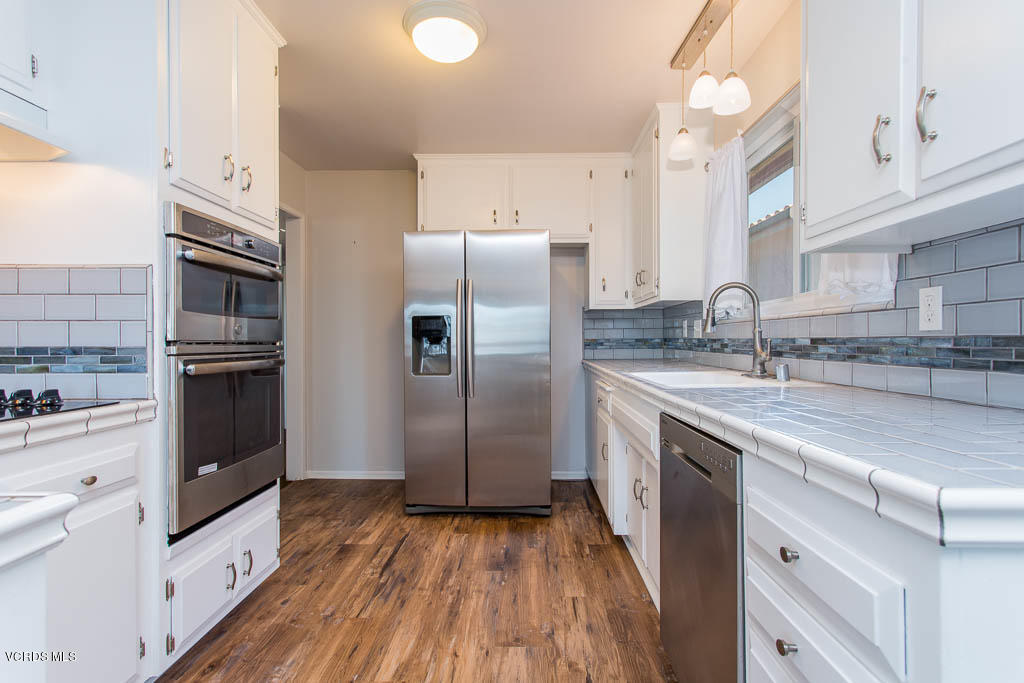 5051 Island View Street Oxnard, CA 93035 - Photo 14 of 38 a kitchen with stainless steel appliances granite countertop a refrigerator a stove and a sink with wooden floors