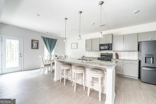 a kitchen with stainless steel appliances granite countertop a stove a refrigerator a kitchen island a sink and a refrigerator