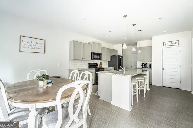 a kitchen with stainless steel appliances kitchen island granite countertop a table chairs and a refrigerator