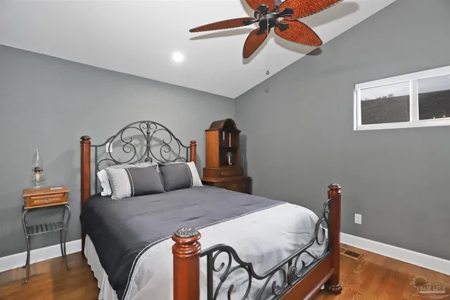 a bedroom with a bed a dresser and wooden floor