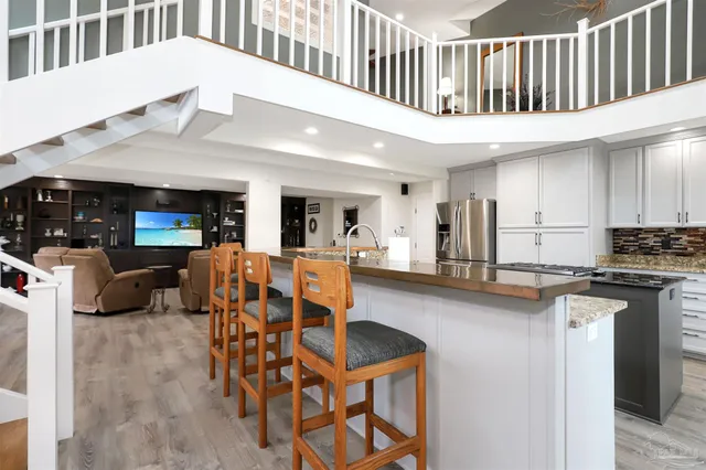 a living room with stainless steel appliances kitchen island granite countertop a table chairs in it and a living room view