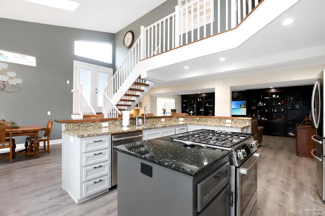 a kitchen with stainless steel appliances granite countertop a stove and a view of living room