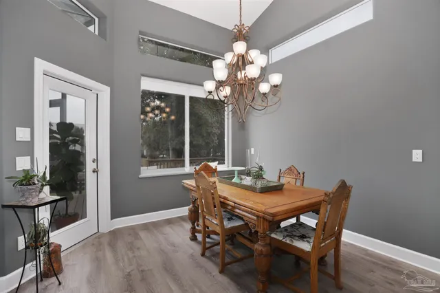 a dining room with wooden floor a chandelier a wooden table and chairs