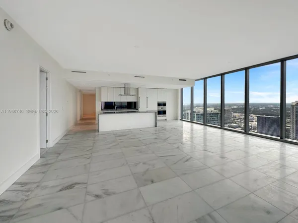 a large white kitchen with granite countertop a coffee maker on granite countertops