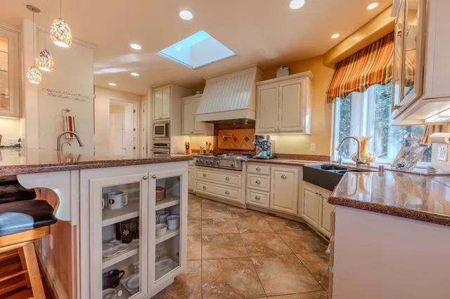 a large kitchen with stainless steel appliances granite countertop a stove and a sink