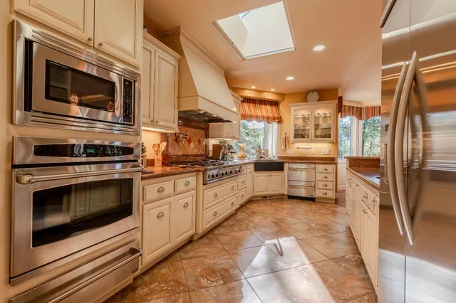 a kitchen with stainless steel appliances granite countertop a stove a sink and a refrigerator