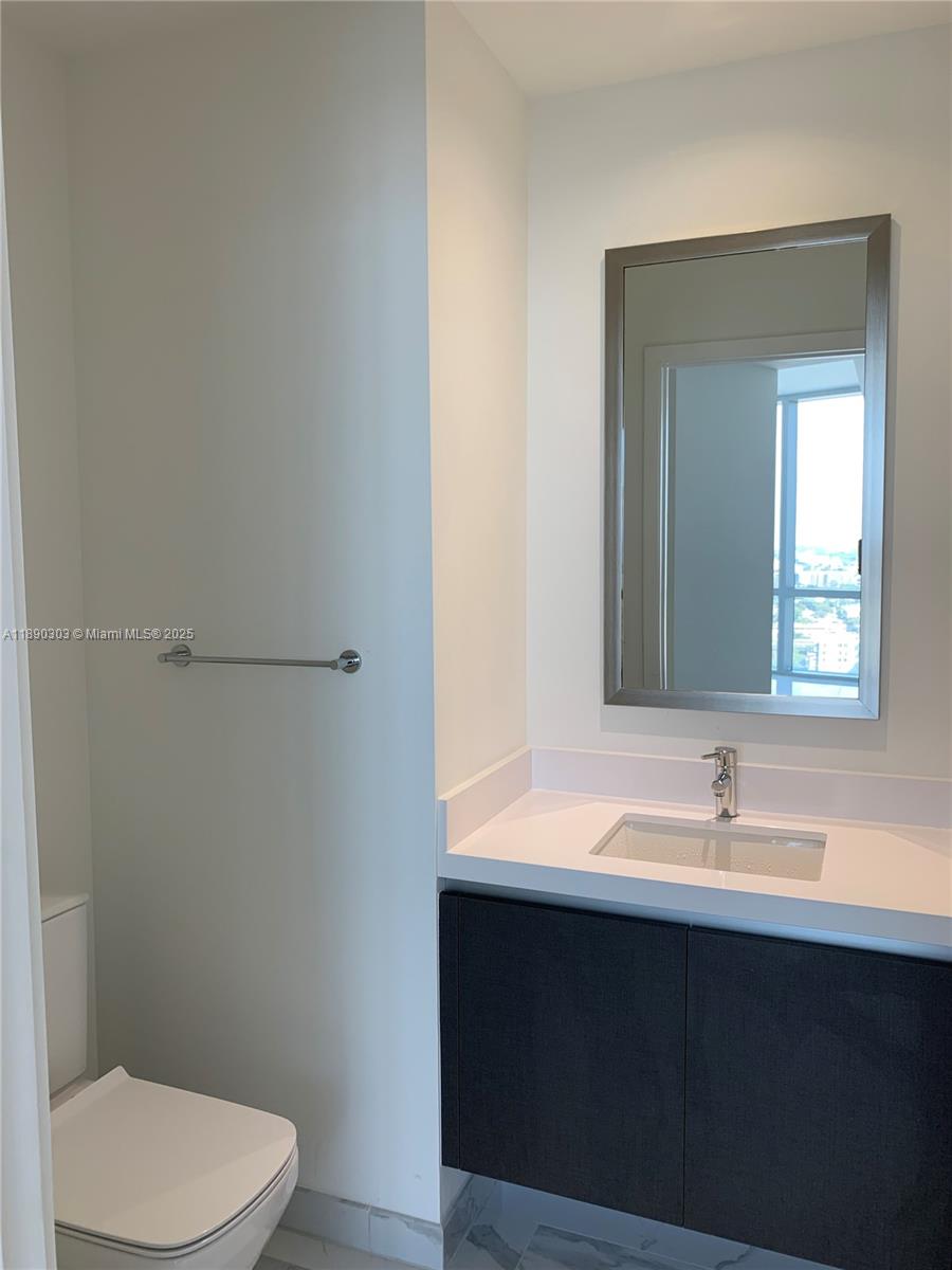 851 Northeast 1st Avenue, Unit 2702 Miami, FL 33132 - Photo 15 of 48 a bathroom with a sink a toilet and mirror