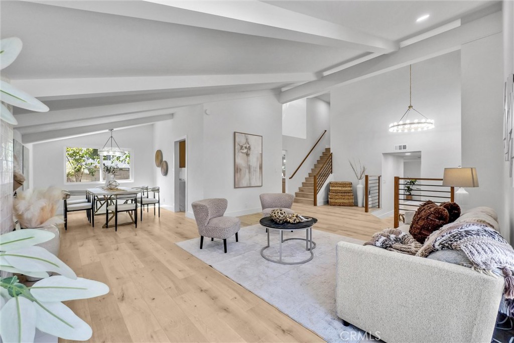 a living room with couches and kitchen view with wooden floor