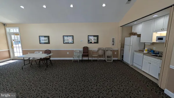 a living room with stainless steel appliances a couch dining table and a refrigerator
