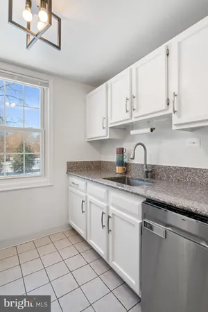 a kitchen with granite countertop white cabinets a sink and dishwasher
