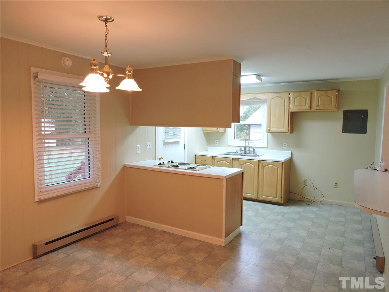179 Clayton Glenn Road Roxboro, NC 27574 - Photo 3 of 14 a room with kitchen island a chandelier stainless steel appliances cabinets and a window