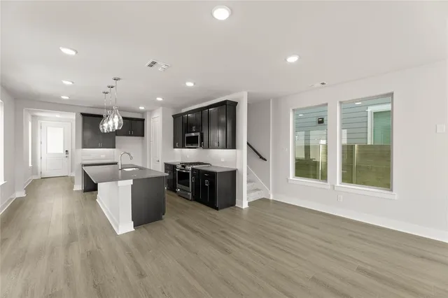 a view of kitchen with stainless steel appliances kitchen island hard wood floors and fireplace