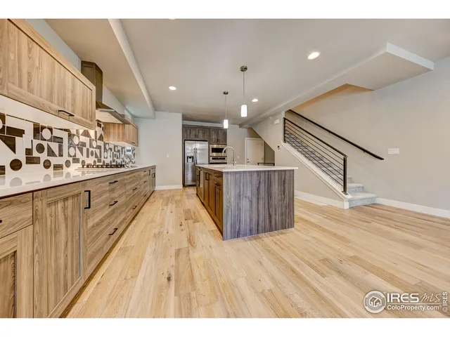 a open kitchen with kitchen island wooden floors granite counter tops and white appliances