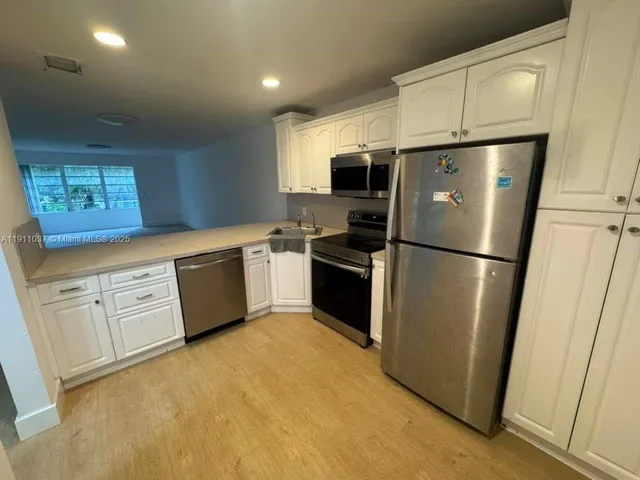 a kitchen with white cabinets stainless steel appliances and a refrigerator