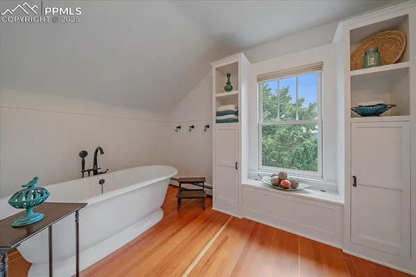 a bathroom with a tub a potted plant on the counter and a window