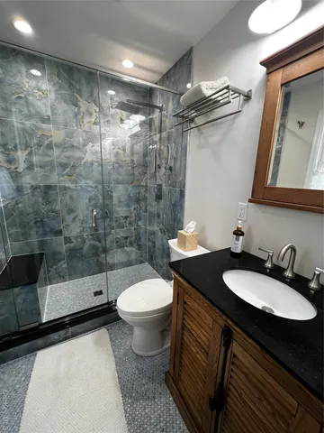 a bathroom with a granite countertop sink toilet a mirror and shower