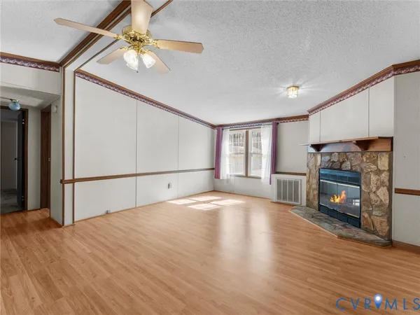 a view of a livingroom with a fireplace a ceiling fan and wooden floor