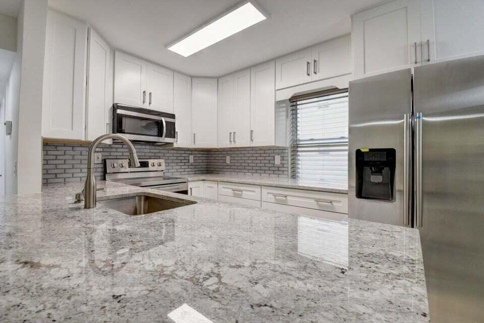 93 Normandy B Delray Beach, FL 33484 - Photo 2 of 44 a kitchen with granite countertop a refrigerator and a stove top oven