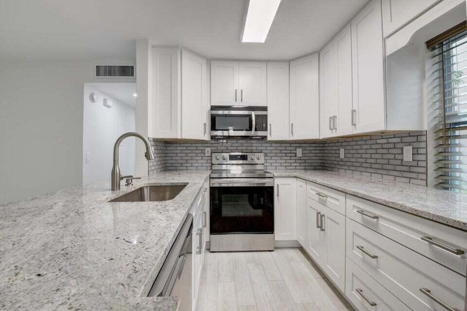 93 Normandy B Delray Beach, FL 33484 - Photo 3 of 44 a kitchen with granite countertop a stove sink and cabinets