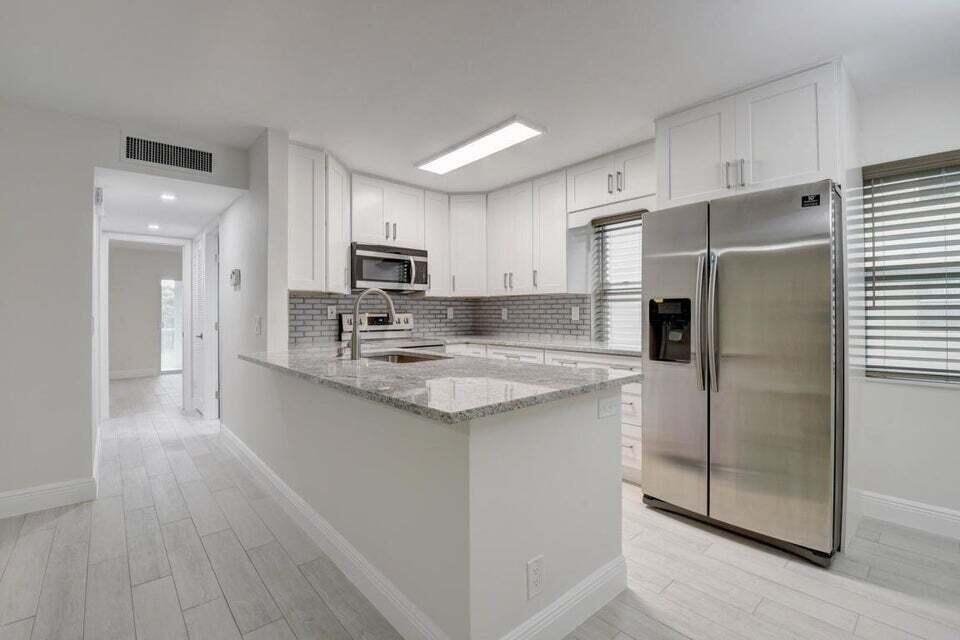 93 Normandy B Delray Beach, FL 33484 - Photo 4 of 44 a kitchen with kitchen island granite countertop a refrigerator a sink a stove a microwave and island